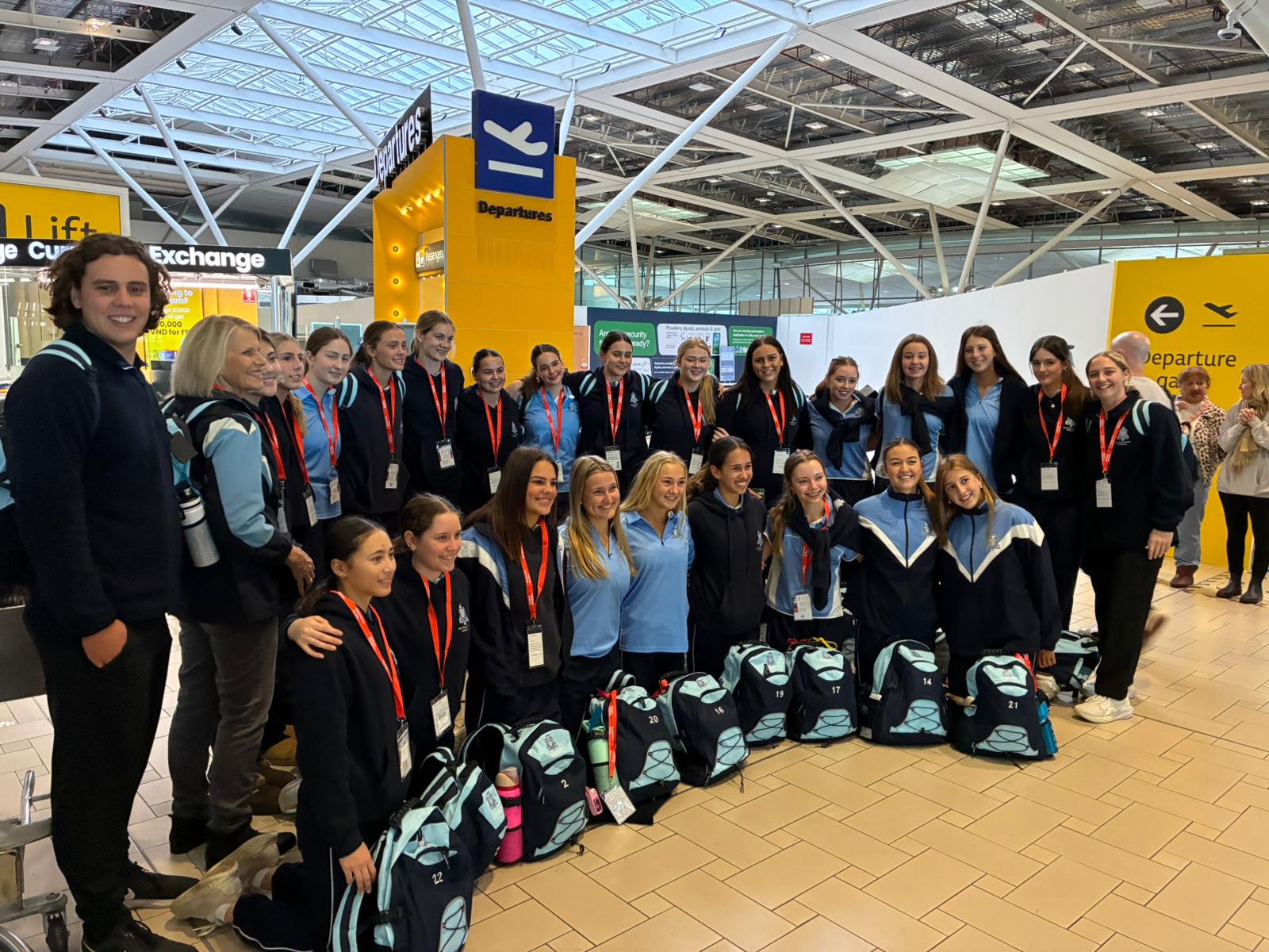 Group photo of All Hallows students at Brisbane Airport departure gate before their flight.